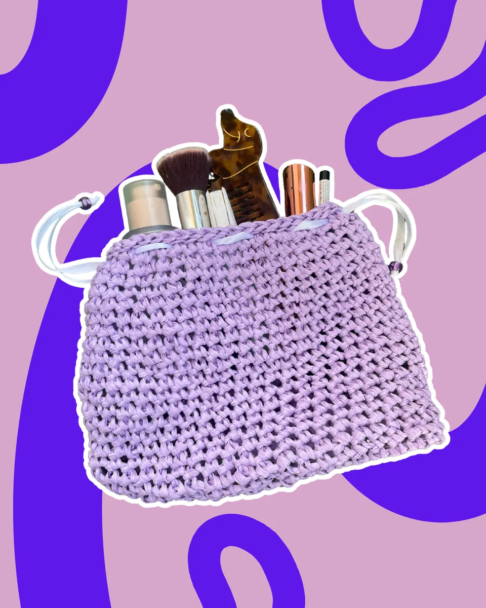 Pochette Trousse in Rafia "Lilac Bloom" — Delicata, capiente e dallo spirito naturale! Questa trousse è lavorata a mano in resistente rafia opaca in una raffinata tonalità lilla pastello. Il design a sacchetto è valorizzato da una lavorazione fitta ma flessibile, ideale per contenere makeup, pennelli, pettini e tutti i tuoi essenziali da viaggio o da borsa. La chiusura regolabile con nastro rasato panna e perline viola a contrasto assicura praticità e stile in un unico gesto.